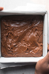 Top view of chocolate fudge in a parchment lined baking tin, process of making chocolate fudge