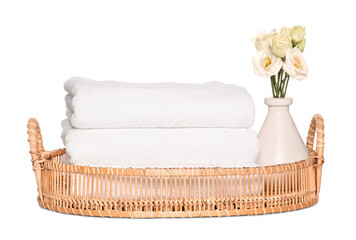 Wicker tray with folded soft terry towels and flowers on white background