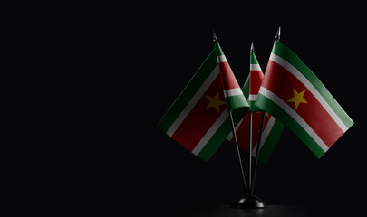 Small national flags of the Suriname on a black background