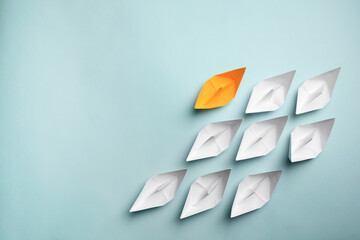 Yellow paper boat among others on light background, flat lay with space for text. Uniqueness concept