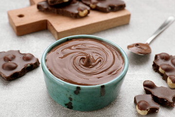 Chocolate pieces and bowl of sweet paste on grey table
