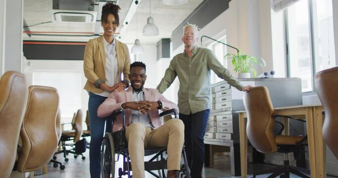 Portrait of happy diverse business people with disabled colleague in creative office