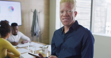 Portrait of happy albino african american businessman with tablet in creative office - Powered by Adobe