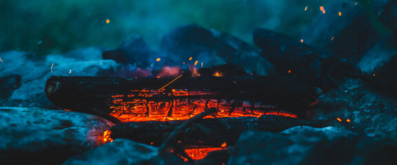 Vivid smoldered firewoods burned in fire close-up. Atmospheric warm background with orange flame of...