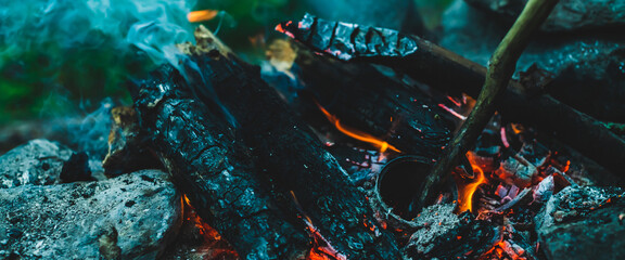Vivid smoldered firewoods burned in fire close-up. Atmospheric warm background with orange flame of...