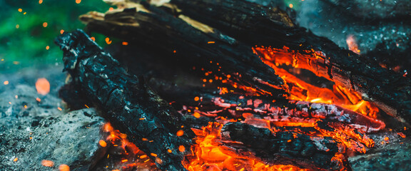 Vivid smoldered firewoods burned in fire closeup. Atmospheric background with orange flame of...