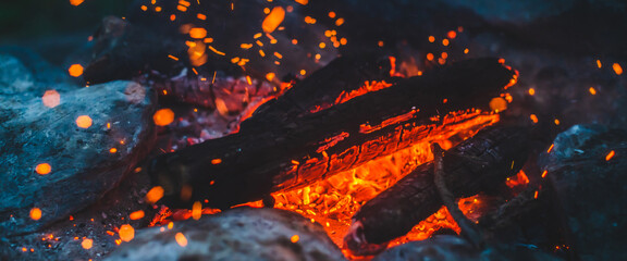 Vivid smoldered firewoods burned in fire close-up. Atmospheric background with orange flame of...