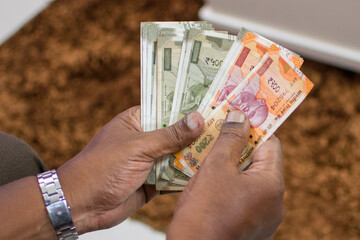 An Indian holding Indian currency (Rupee) notes of various denominations in hands and counting. 