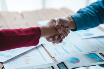 Close up bookkeepers working with balance sheet to analyze problems and find solutions to bringing develop business organization and company's stock market system. Shaking hands after agreement