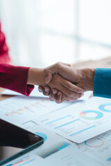 Close up bookkeepers working with balance sheet to analyze problems and find solutions to bringing develop business organization and company's stock market system. Shaking hands after agreement