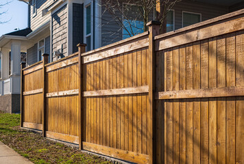 Nice wooden fence around house. Wooden fence with green lawn. Street photo