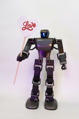 Curious gray robot shows a sign with the word love in red letters