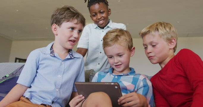 Video of happy diverse boys using tablet at school