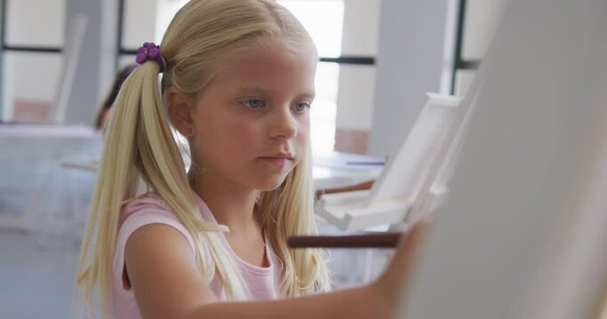 Video of focused caucasian girl painting during art lessons at school