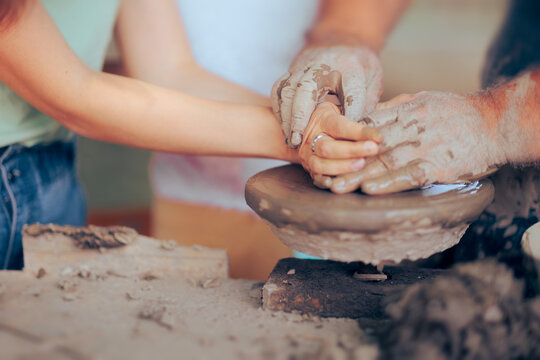 Hands Shaping a Pot Together in a Pottery Class. Master and student making a clay object learning about artistic craft 

