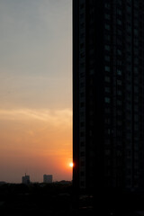a sunset scene, half of the frame is filled with tall urban buildings.