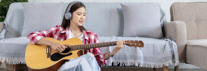 Asian female artist playing the guitar and singing happily in the living room, Relaxation with...