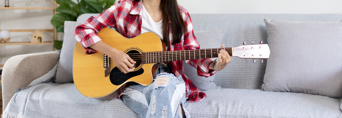 Asian female artist playing the guitar and singing happily in the living room, Relaxation with...