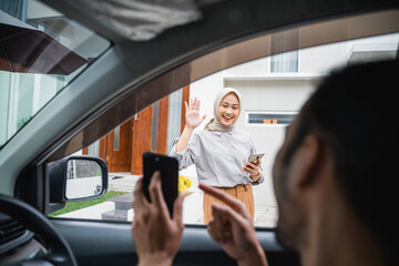 veiled woman waves to an online transportation driver when he comes to pick her up
