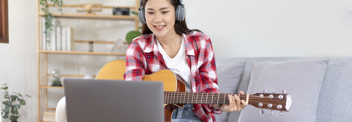 Woman artist playing the guitar and live or stream on laptop in the living room, Relaxation with...