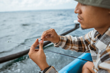 angler puts bait on a hook while casting on a small fishing boat at sea
