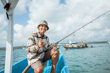 angler smiling with thumbs up while sitting on a small fishing boat at sea