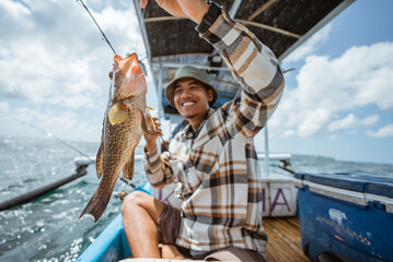 big grouper caught by an Asian angler with a fishing rod