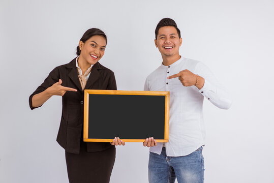 asian couple holding the blackboard together with pointed finger on isolated background