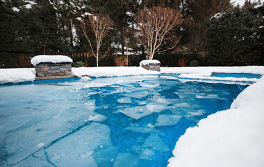 Pool with ice and slush after snow storm. Inground pool with pool cover and ice layer in backyard...