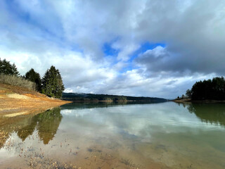 Scenic landscape of cloudy reflection on lake water with trees and forest in the background in Portland Oregon