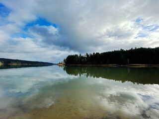 Scenic landscape of cloudy reflection on lake water with trees and forest in the background in Portland Oregon