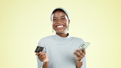 Phone, credit card and face of a black woman in a studio doing online shopping for sale or discount. Happy, smile and African female buying from ecommerce website with cellphone by yellow background.