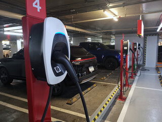 Indoor parking lot with electric vehicle charging stations available, automotive technology concept. © Pond Thananat