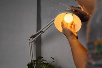 Handyman choosing between energy save and cheap incandescent lamp while changing light in the...