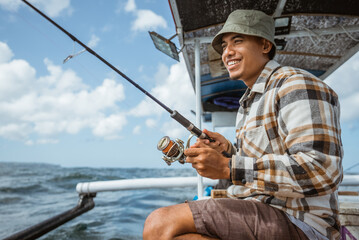 Obraz premium fishermen reel in fishing line while casting on a small fishing boat at sea