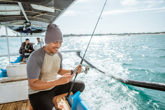 angler using cell phone while fishing at sea with small fishing boat