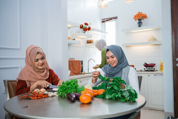 woman wearing hijab with best friend preparing food for dinner in the kitchen