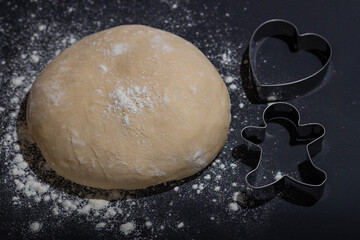 raw homemade dough against a dark background with cutters, cookie dough,