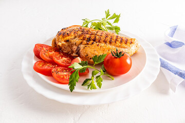 front view of a plate with juicy grilled chicken fillet and tomato slices. delicious healthy food without cooking in oil. diet.