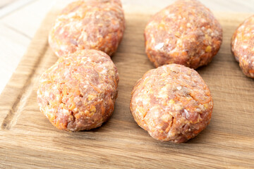 raw homemade meatballs on a massive board made of natural wood