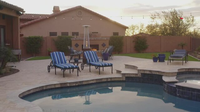 A desert landscaped backyard located in Arizona featuring
a travertine tiled pool deck outdoors kitchen and fireplace.