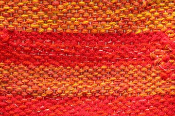 Woven red and orange wool fabric texture. Hand knitted textile canvas background. Patchwork carpet...