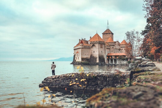 Montreux, Switzerland - December 8, 2022: Male tourist standing and looking at Chillon Castle at Geneva lake, Montreux, Switzerland, Travel concept.