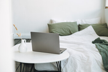 Opened laptop in scandinavian modern cozy bright interior in bedroom at home