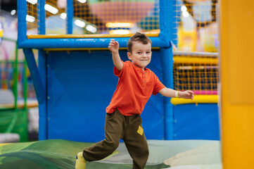 A happy boy jumps on a trampoline in an entertainment center.