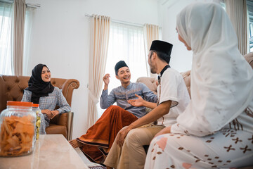 Muslim couple visiting to celebrate Eid and chatting with the host while sitting