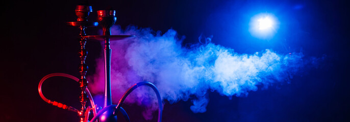 Hookah, shisha on a smoky black background with neon lighting and smoke. Place for your text,...