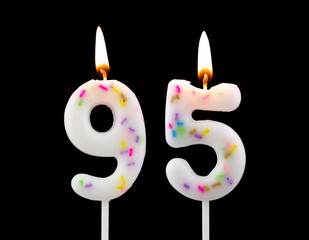 White decorated burning birthday candles on black background. Number 95.