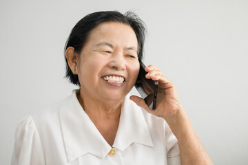 Smiling Asian elderly woman while talking on mobile phone showing happy mood.