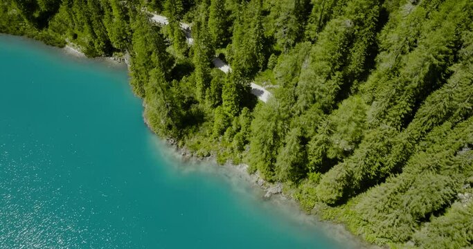 Aerial drone shot of the blue river going to a pine forest, Lago di Braies, Italy, Dolomites